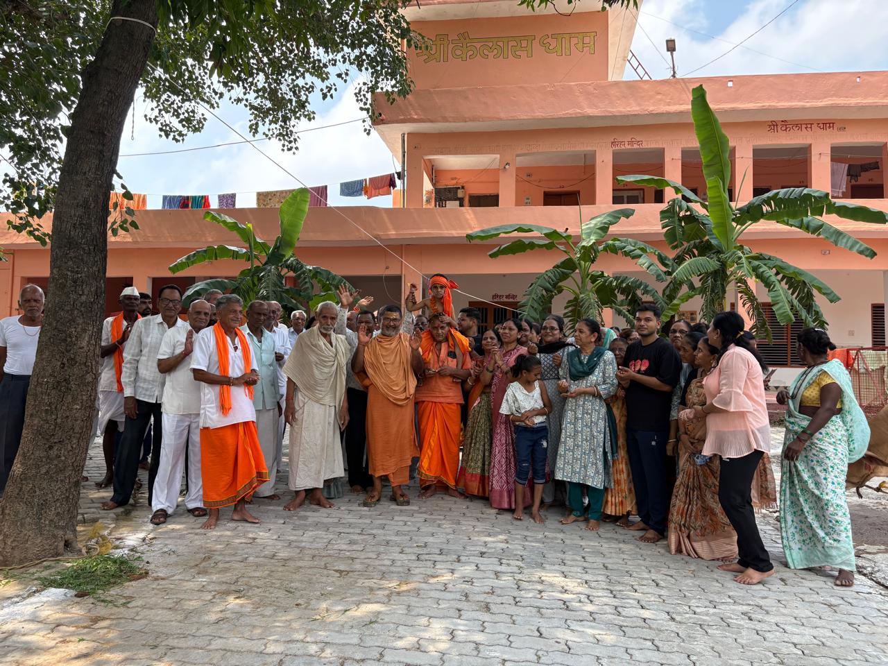 Sangat gathered before the Shri Kailas Dham building with Guruji and sants after the utsav — उत्सव के पश्चात श्री कैलास धाम भवन के समक्ष गुरुजी एवं संतों के साथ एकत्र संगत